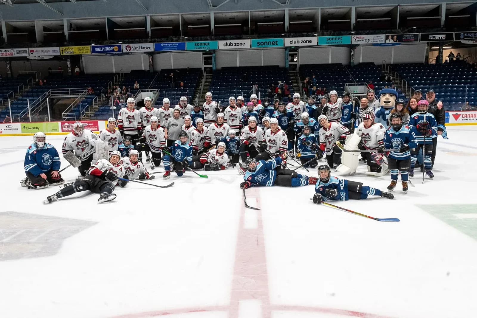 Guelph Giants players and community partners posing for a group photo on the ice