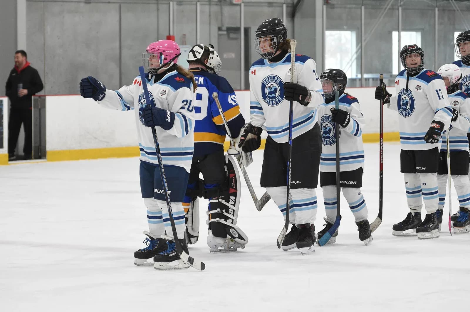Guelph Giants players in white jerseys gathered on the ice