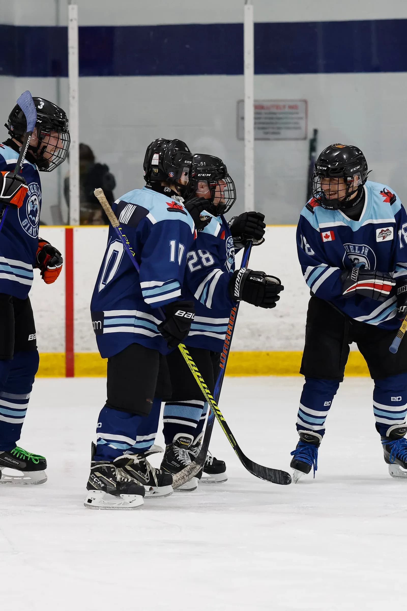 Guelph Giants players in blue jerseys gathered together on the ice